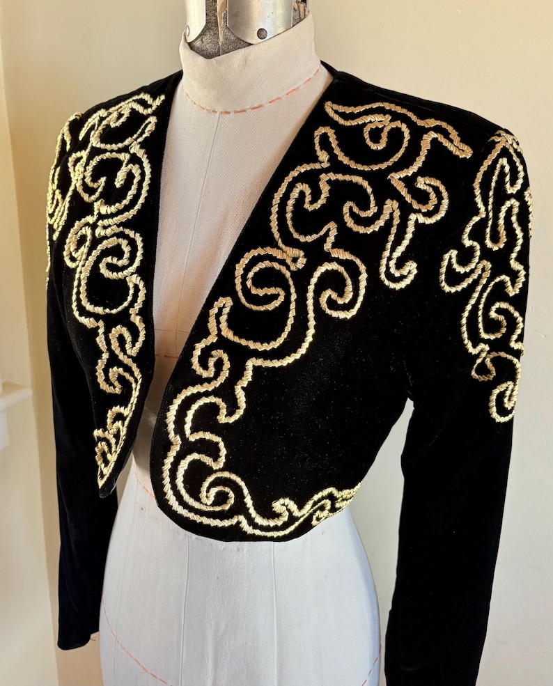 a black bolero shrug with white embroidery